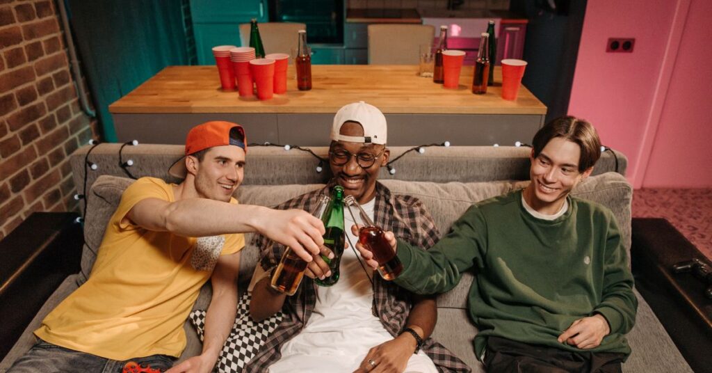 Movies like Hangover: three friends clinking beer bottles at a party